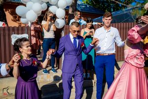 Guests in formal attire dance together at an outdoor celebration with white balloon decorations.
