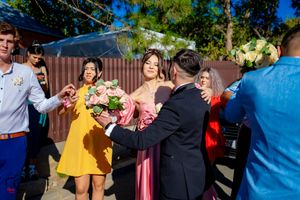 Wedding party celebrates outdoors with pink bouquets and festive atmosphere.