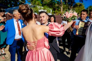 Guests celebrate at outdoor wedding reception with pink dress and floral bouquets.