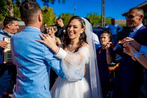 Joyful wedding celebration outdoors on sunny day with guests watching.