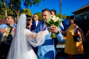 Festive outdoor wedding scene with guests and accordion player in background.