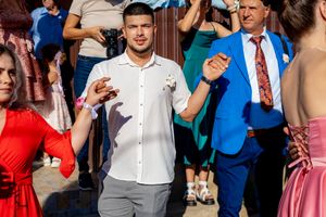 Guests in formal attire dancing at sunny outdoor wedding reception.