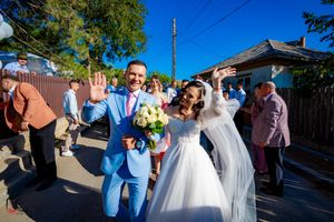 Joyful wedding celebration with guests waving and taking photos on a sunny afternoon.