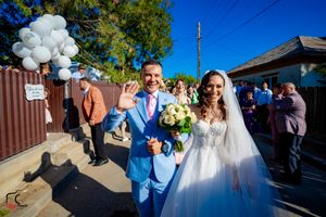 Wedding party and guests celebrating outdoors with white balloons under bright blue skies.