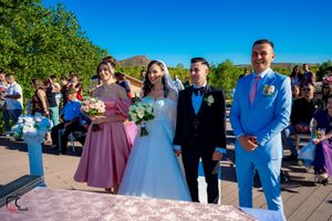 Wedding group in coordinated blue and purple attire gathered for formal photos by the water.