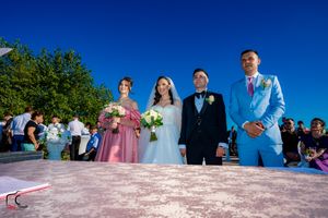 Wedding party members line up in coordinated attire for photos on a sunny waterfront deck.