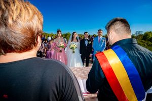 Outdoor wedding ceremony with attendants lined up against vibrant blue sky and mountain backdrop.