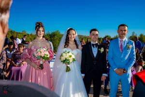 Wedding party members in formal attire standing in line during outdoor ceremony.