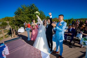 Wedding celebration on outdoor patio with guests and wedding party under clear blue skies.