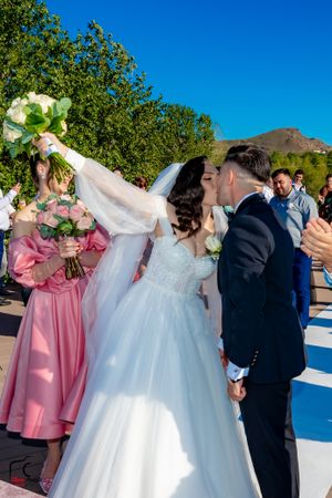Wedding party arranged on outdoor platform with bridesmaids in pink and white floral bouquets.