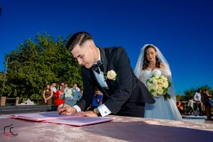 Marriage certificate signing moment during outdoor wedding with mountain scenery.