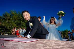 Playful wedding ceremony moment during document signing with mountains in background.