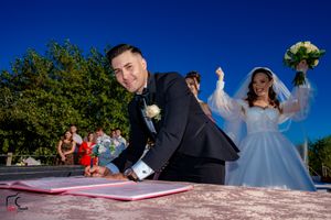 Wedding ceremony signing moment captured from unique low angle against bright blue sky.
