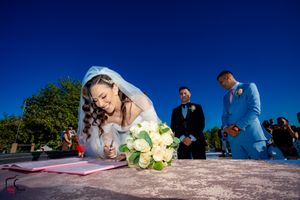 Outdoor wedding signing ceremony photographed from below against vibrant sky.