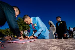 People gather to sign marriage documents on a sunny day with vibrant blue skies.