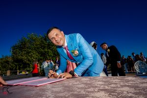 Person in light blue attire signs paperwork at an outdoor ceremony.
