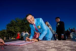 Wedding party members sign official documents during an outdoor celebration.