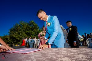 Outdoor wedding ceremony with document signing against clear blue skies.