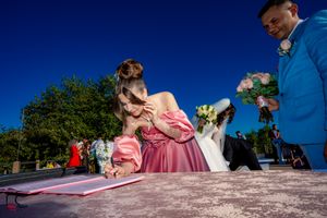 Wedding celebration participants sign papers during outdoor ceremony.