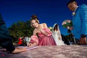 Guests and wedding party members participate in document signing outdoors.