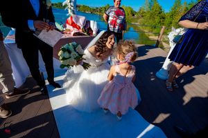 Wedding celebration with floral decorations and guests on wooden deck by water.