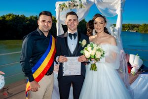 Wedding party with Romanian flag detail gathering on waterfront deck for formal photos.