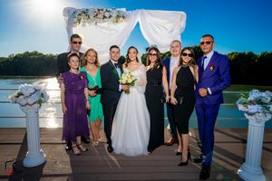 Summer wedding celebration photos with guests on waterfront deck under blue skies.