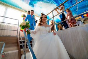 Wedding celebration aboard a boat with decorative white drapes and blue ceiling.