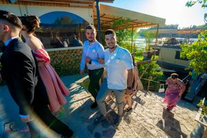 Wedding guests dance together outdoors under a covered patio area during a celebration.