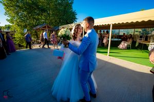 Guests gather on a patio for an outdoor wedding reception with mountains in the background.
