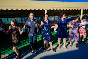 Wedding guests dance in rows during a group dance at an outdoor reception.