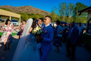 Outdoor wedding reception with mountain backdrop as guests celebrate on the patio.