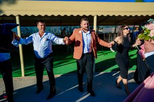 Guests perform synchronized dance moves at an outdoor wedding reception.