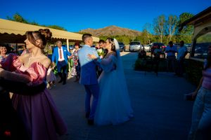 Wedding celebration panorama showing mountains and guests dancing under blue skies.