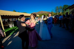 Panoramic view of wedding guests dancing at an outdoor venue with mountain scenery.