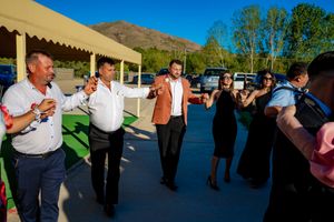Wedding guests dance in formation during an outdoor reception with mountain views.