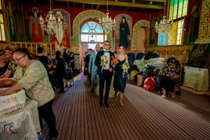 Wedding guests mingle inside a decorated orthodox church with striped carpet and religious icons.