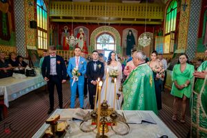Traditional Orthodox wedding service with clergy in green robes surrounded by attendees in formal attire.