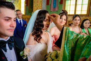 Intimate moment during Orthodox wedding ceremony with decorative church interior visible in background.