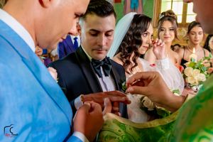 Wedding ceremony guests gather in an ornate venue with decorative lighting and floral arrangements.