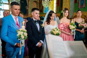 Wedding ceremony participants stand together in an elaborately decorated historic venue with gilded details.