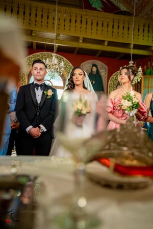 Wedding party members line up in an ornate venue with decorative ceiling details and soft lighting.