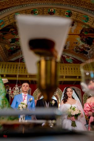 Wedding celebration viewed through decorative elements with golden ornate ceiling details visible above.