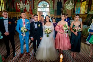 Wedding party gathered in a historic venue with stained glass windows and ornate architectural details.