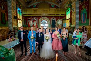 Panoramic view of a wedding celebration in an ornate historic ballroom with decorative ceiling and columns.