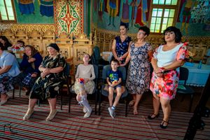 Wedding guests stand in a beautifully decorated ornate church hall with striped flooring and gilded walls.