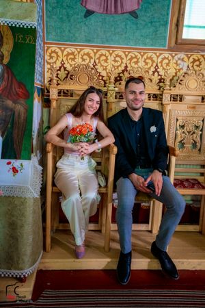 Couple sits casually on wooden benches in an ornately decorated church interior with gilded details.