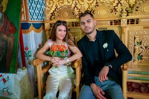 Couple relaxes on wooden church benches surrounded by decorative gold trim and painted walls.