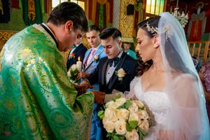Orthodox wedding ceremony takes place in an ornate church with green and gold decor.