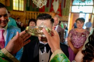 Wedding ceremony guests participate in a traditional crown ritual during an Orthodox Christian ceremony.